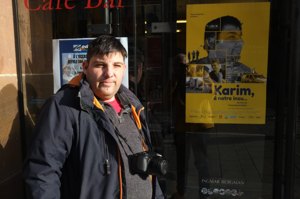 Karim devant l'affiche du documentaire "Karim à notre insu
